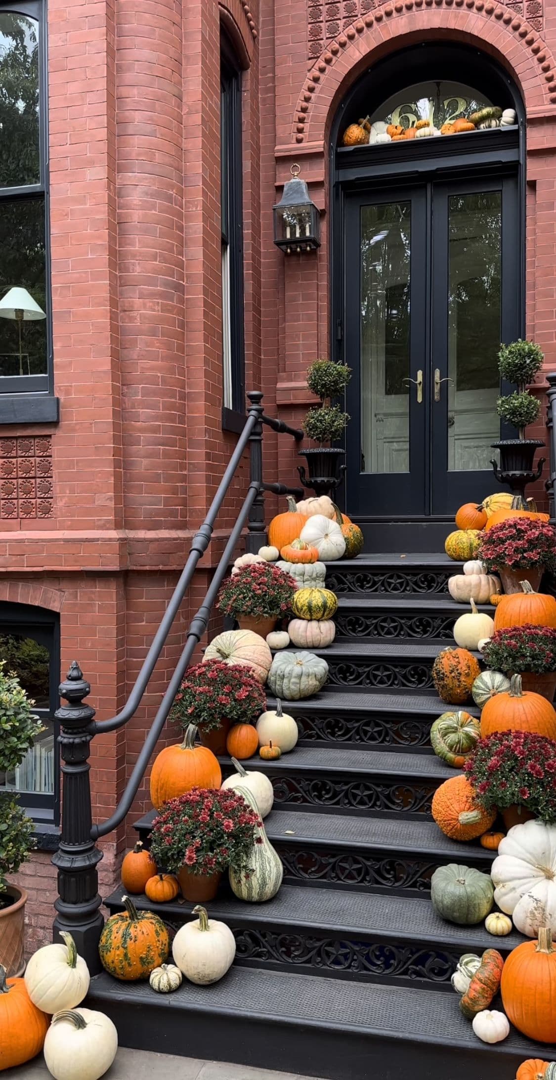 Large front entry styled with hay bales, cornstalks, and pumpkins.