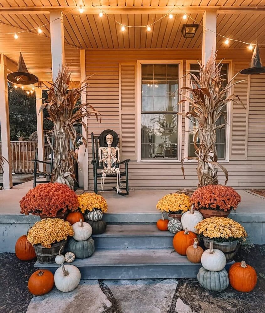 Mid-sized porch decorated with layered pumpkins, mums, and fall lanterns.